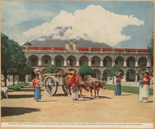 People with oxen and cart in plaza, with volcano in background