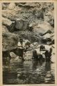 Group bathing next to rocky shoreline