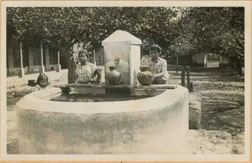 Two women and girl at a well