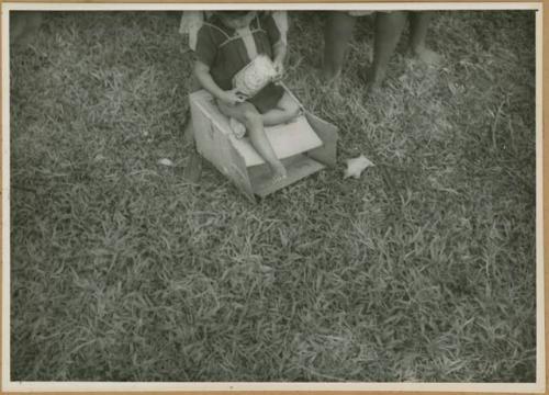 Ngobe-Bugle child sitting on box holding Fine Old Whisky Rye bottle