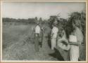 Ngobe-Bugle standing in field, one man carrying jaguar on back and holding bottle of gin