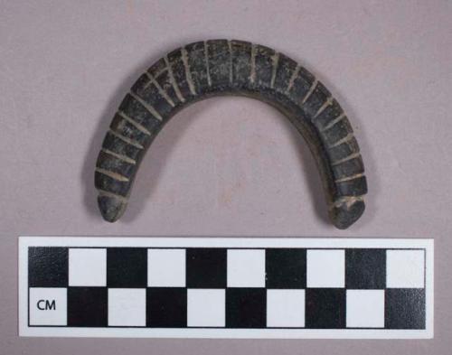 Ground stone, incised crescent shaped ornament