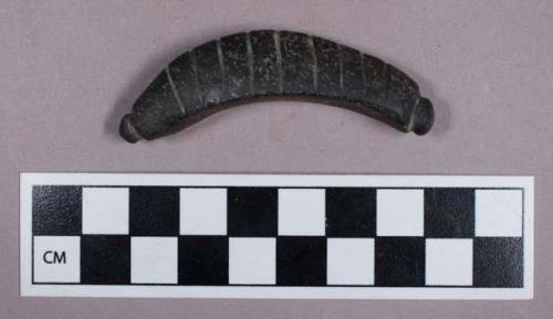 Ground stone, incised crescent shaped ornament