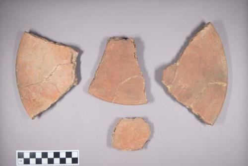 Earthenware plate sherds with red paint decoration on interior; foot ring base.