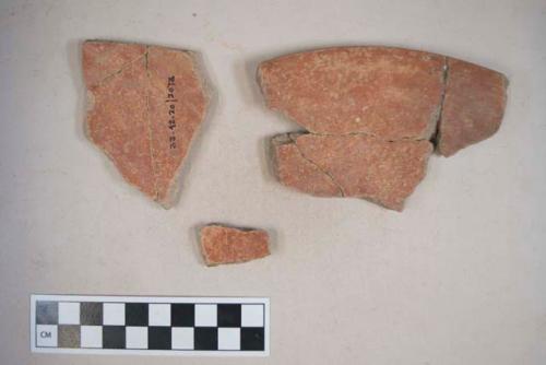 Earthenware vessel rim and body sherds with red paint decoration on interior and exterior.