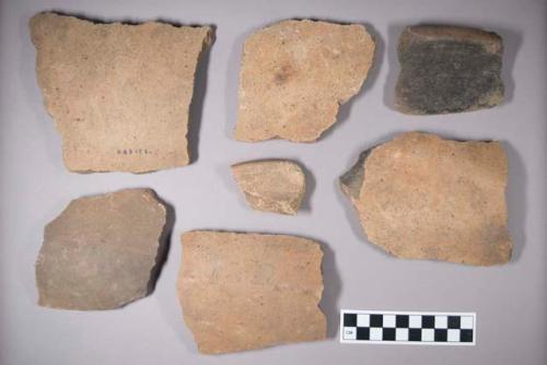Earthenware vessel rim and body sherds; mostly buff colored; some with charring.