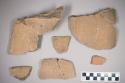 Body and 25 sherds of burial urn of gray, sandy ware, unslipped; red paint on li