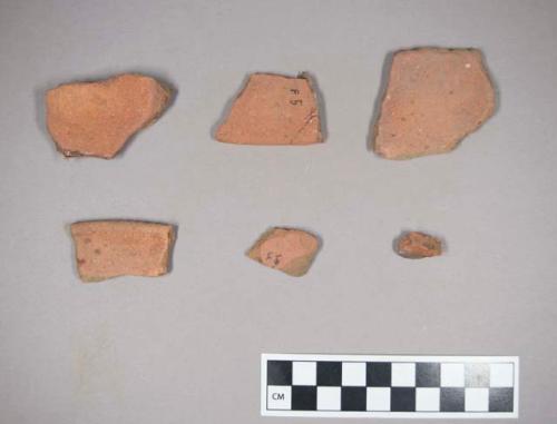 Restored section (& 3 sherds) of a red sandy ware dish which shows traces of red