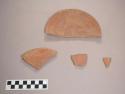 Earthenware vessel body and rim sherds. Red paint decoration interior and exterior. Plate-like shape. Possible pot cover.