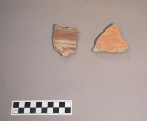 Earthenware vessel base and rim sherds. Base is red painted interior and exterior. Rim sherd is painted polychrome design on exterior.