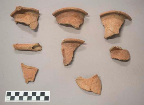 Earthenware vessel body and rim sherds. Red painted exterior and interior.  Tubular spout piece. Flared rim sherds.