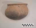Earthenware vessel rim and body sherds. Red painted rim. Charred exterior and bottom of interior. Many pieces refit. Some flared rim sherds decorated with incised linear designs and modeled appliques.