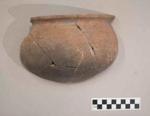 Earthenware vessel rim and body sherds. Red painted rim. Charred exterior and bottom of interior. Many pieces refit. Some flared rim sherds decorated with incised linear designs and modeled appliques.