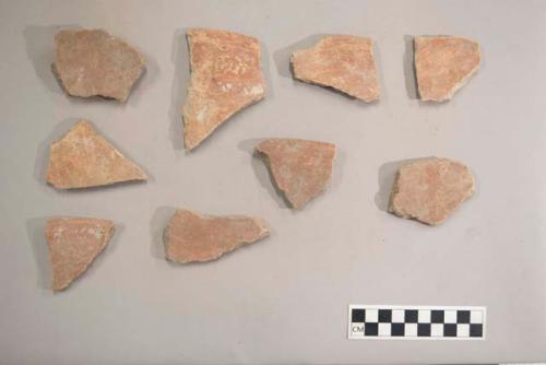 Earthenware vessel rim and body sherds. Red paint interior and exterior.