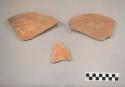 Earthenware vessel rim and body sherds with red paint interior and exterior. Charring.