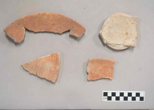 Earthenware vessel rim and base sherds. Rim sherds painted red interior and exterior. Foot ring base undecorated with some charring.