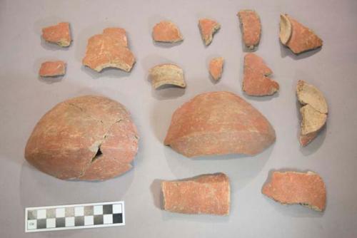 Earthenware vessel body, rim, shoulder, and foot ring base sherds. Red painted exterior.