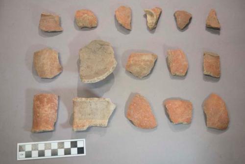 Earthenware vessel rim, body, and foot ring base sherds. Red painted exterior.