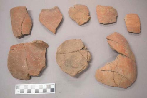 Earthenware vessel base, rim and body sherds. Red painted exterior, undecorated interior. Some sherds slightly charred.