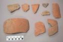 Earthenware vessel body sherds with red paint exterior decoration. Some with interior charring.