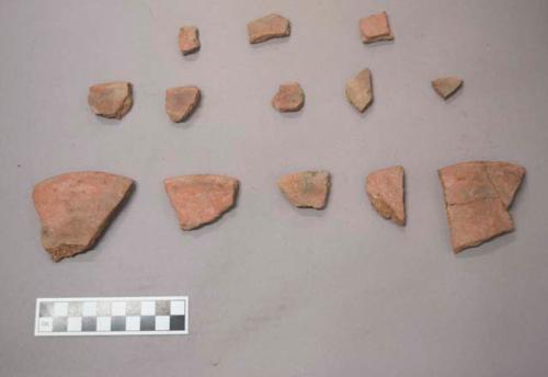 Earthenware vessel rim and body sherds with red paint interior and exterior.