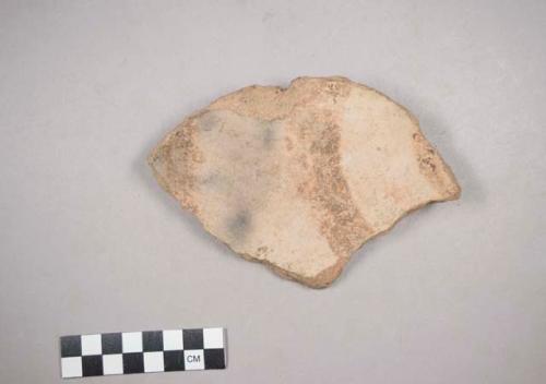 Earthenware vessel foot ring base sherd. Red painted exterior with brown painted design on white painted interior.