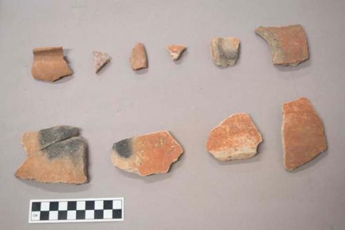 Earthenware vessel body, base and rim sherds with red paint exterior decoration. Some with charring and some with polychrome decoration.