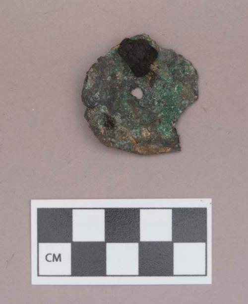 Metal, copper alloy ear spool fragment, with charcoal fragment adhered to one side