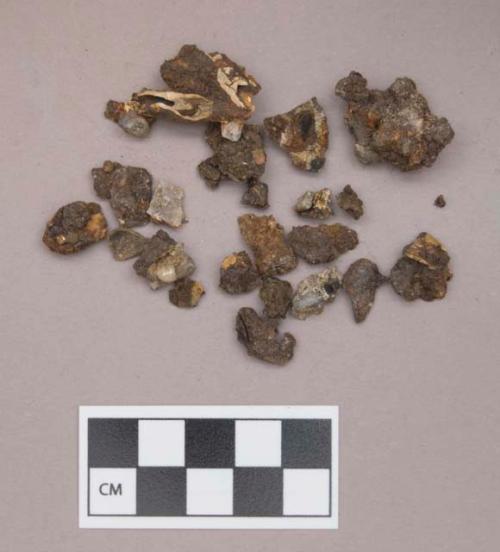 Metal, iron fragments, copper sheet fragment, some with mica, shell beads, pearls, charcoal, and perforated animal teeth adhered; some metal fragments appear to be worked