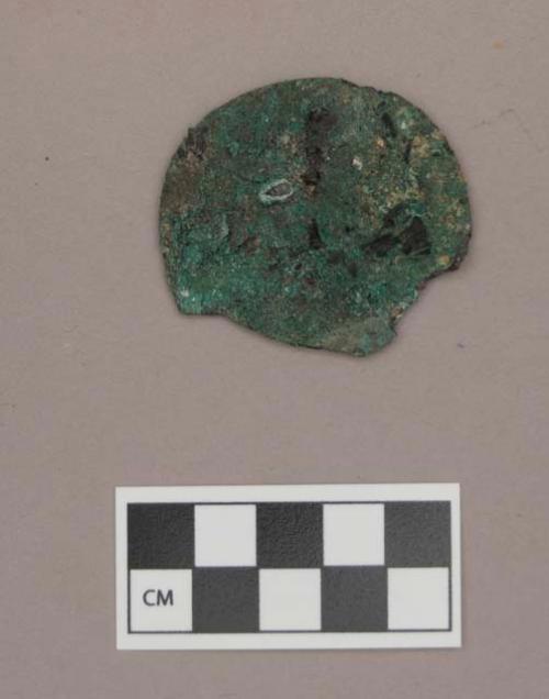 Metal, copper alloy disc fragment, flat, with burned and calcined bone and charcoal adhered to it