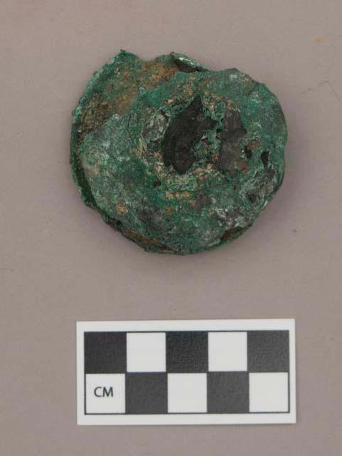 Metal, copper alloy ear spool, with fragments of charcoal and calcined bone adhered to it