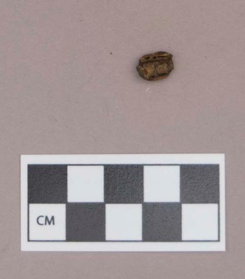 Shell bead fragment, stained by iron, with iron fragment inside bead