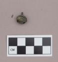 Metal, copper alloy bell, round, two perforations on bottom, loop on top; fabric fragment