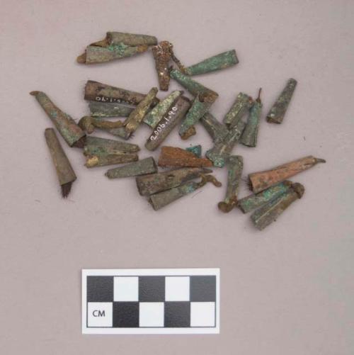 Metal, copper alloy rolled tinkler cones, with possible leather strip through some, some with hair inside; one iron cone fragment