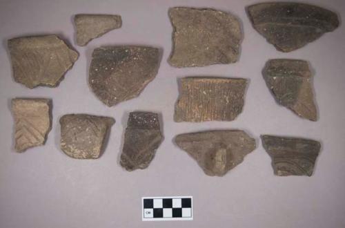 Ceramic, earthenware rim, body, and handle sherds, some incised, some incised and cord-impressed, some with possible Ramie design, some cord-impressed, some undecorated, one with impressed rim, shell-tempered