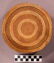 Basket, shallow bowl, circular pattern, woven grass, edges trimmed