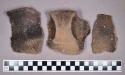 Ceramic, earthenware rim and body sherds, shell-tempered, cord-impressed, incised, and punctate, strap handles, two perforated, one stained with red ochre; and one ground stone fragment with "X" shaped abrasion marks