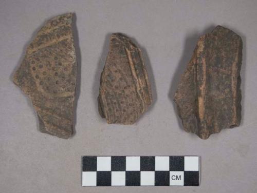 Earthenware rim and body and base sherds with carved designs
