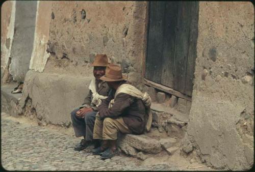 Two men sitting in front of doorway