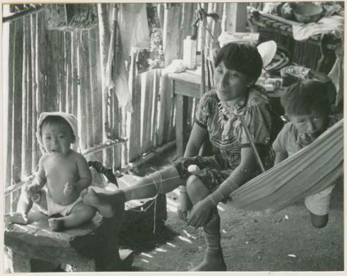 Woman putting on beads, child (left) has painted nose and forehead