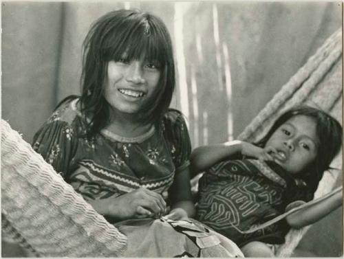 Two girls learning to sew on hammock