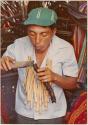 Kantule helper lights roll of tobacco for chicha fiesta ceremonial smoking