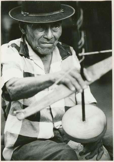 Man drilling holes in gourd to make a strainer