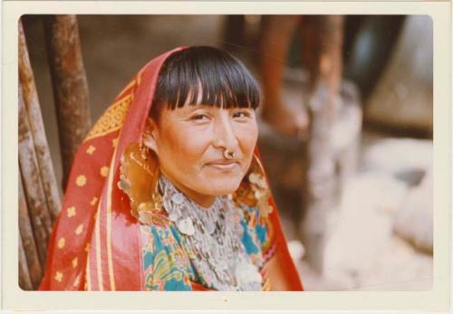 Woman in gala dress, displaying gold nose rings, earrings, and coin necklace