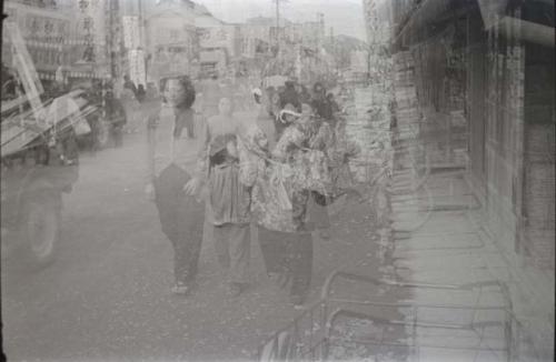 Women walking down street, with storefronts in background