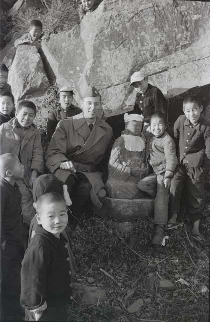 George Butler with group of children and Buddha statue