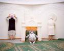 "Women caress the limestone walls of the Aq Meshit mosque while praying that their relations recover from illness. Zhylyoi District, Kazakhstan, 2014"