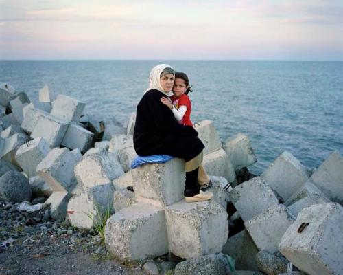 "A woman and her granddaughter sit on the artificial seawall, a few yards from the Iranian border. Astara, Azerbaijan, 2010"