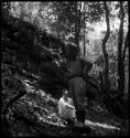 Two men on side of hill or overgrown structure