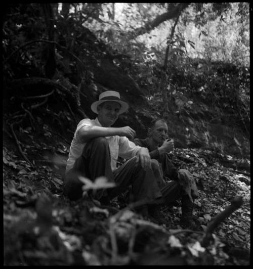 Two men on side of hill or overgrown structure